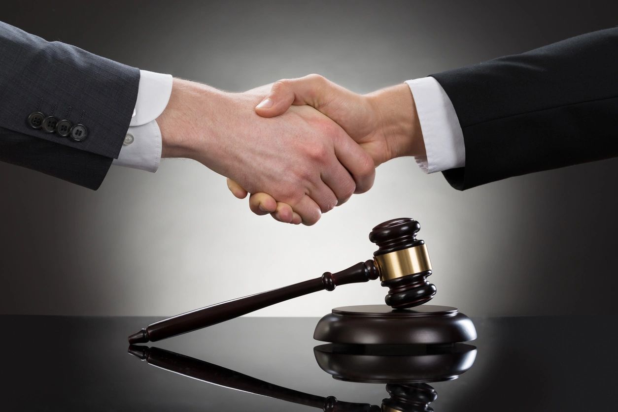 Two people shaking hands over a gavel.
